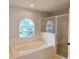 Bright bathroom features a soaking tub beneath an arched window and a glass-enclosed shower at 511 Elbridge Pl, Kissimmee, FL 34758