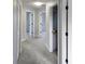 Carpeted hallway with white doors featuring modern black hardware and freshly painted gray walls at 511 Elbridge Pl, Kissimmee, FL 34758