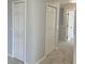 Hallway with carpet floors featuring multiple white closet doors with access to other rooms at 511 Elbridge Pl, Kissimmee, FL 34758