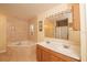 Bright bathroom showcasing a tiled tub and double vanity with ample lighting at 5572 Myakka Ave, Intercession City, FL 33848