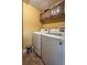 Efficient laundry room with modern washer and dryer, complemented by overhead storage cabinets at 5572 Myakka Ave, Intercession City, FL 33848