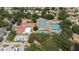 Aerial view of community featuring pool, tennis courts, clubhouse, and parking surrounded by lush trees at 5919 Mcenroe Ct, Leesburg, FL 34748