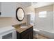 Bathroom with granite countertop vanity, round mirror, white cabinets, and a tub/shower combo with white tile at 5919 Mcenroe Ct, Leesburg, FL 34748