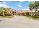 Beautiful clubhouse exterior with well-manicured landscaping, circular driveway, covered entrance, and flag pole at 5919 Mcenroe Ct, Leesburg, FL 34748