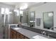 Bathroom with double sinks, gray counter tops, wooden cabinets, and a glass enclosed shower at 6617 Harper Way, Harmony, FL 34773