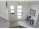 Bright foyer features tile floors, glass door, modern table and mirror, and window with plant at 6617 Harper Way, Harmony, FL 34773