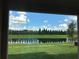 Picturesque view of a calm pond reflecting the blue sky, framed by a covered patio at 6806 Trellis Vine Loop, Windermere, FL 34786