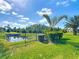 Landscaped backyard with a black fence and palm trees overlooking a tranquil lake with lush greenery at 772 San Raphael St, Kissimmee, FL 34759