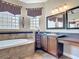 Bright bathroom features a tiled tub, vanity with a sink, and decorative mirrors at 772 San Raphael St, Kissimmee, FL 34759