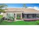 Back exterior featuring a tile roof and screened-in lanai surrounded by lush landscaping at 772 San Raphael St, Kissimmee, FL 34759