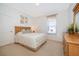 A cozy bedroom with neutral walls, carpet, and wooden dresser and headboard and sunny window at 8217 Fan Palm Way, Kissimmee, FL 34747