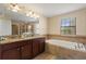 Bathroom with dual sinks, granite countertops, soaking tub, and a large window at 9163 Wedge Dr, Davenport, FL 33896
