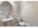 Powder room with pedestal sink, standard toilet, and round decorative mirror at 9163 Wedge Dr, Davenport, FL 33896
