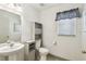 Cozy half-bathroom featuring a modern sink and toilet, storage shelf and window at 1038 Sabine Pl, Kissimmee, FL 34759