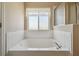Well-lit bathroom featuring a soaking tub, tiled walls, and a window for natural light at 1038 Sabine Pl, Kissimmee, FL 34759