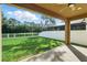 Outdoor view of covered patio and lush green backyard with white fence and trees at 12867 Woodmere Close Dr, Windermere, FL 34786
