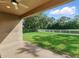 Outdoor view of covered patio with ceiling fan and lush green backyard with white fence at 12867 Woodmere Close Dr, Windermere, FL 34786
