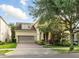 Charming home featuring a two-car garage, brick driveway, and mature landscaping at 12867 Woodmere Close Dr, Windermere, FL 34786