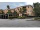 Three-story building with colorful, light-orange walls, a landscaped garden, and a carport at 13500 Turtle Marsh Loop # 825, Orlando, FL 32837