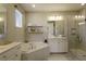 Bright bathroom featuring a soaking tub, tiled shower with glass door, and dual sink vanity at 15079 Guava Bay Dr, Winter Garden, FL 34787