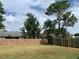 Large backyard with mature trees and a wooden fence, perfect for recreation at 1561 Cypress Woods Cir, St Cloud, FL 34772