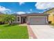 Charming single-story home featuring a well-manicured lawn, brick pathway, and attached two-car garage at 2040 Patriot Way, St Cloud, FL 34769