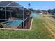 Landscaped backyard with a screened-in pool area and view of the pond at 2206 Hunters Greene Dr, Lakeland, FL 33810