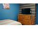 Bedroom featuring blue walls, TV over a wooden dresser, and a soft bed at 2206 Hunters Greene Dr, Lakeland, FL 33810