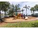 A vibrant community playground with slides and play structures, surrounded by mature trees at 2301 Butterfly Palm Way # 303, Kissimmee, FL 34747