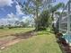Beautiful backyard view with lush green grass, mature trees, and a glimpse of the pool area at 2408 Saint Augustine Blvd, Haines City, FL 33844