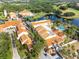 Aerial view of resort buildings with terracotta roofs, palm trees, and a luxurious pool area near a lake at 247 Bell Tower Xing W, Poinciana, FL 34759