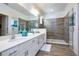Bright bathroom with double vanity, granite counters, tiled floor, plus glass shower with tile surround at 2649 Calistoga Ave, Kissimmee, FL 34741