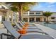 Beautiful poolside lounging area with modern furniture, tropical plants, and a view of the community clubhouse at 2649 Calistoga Ave, Kissimmee, FL 34741