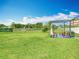 Backyard featuring a pergola with seating, surrounded by a lush green lawn and mature trees at 302 E Drury Ave, Kissimmee, FL 34744
