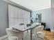 Dining room features a modern glass table, white chairs, and large windows for ample natural light at 302 E Drury Ave, Kissimmee, FL 34744