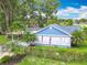 Charming light blue home with lush tropical landscaping and an enclosed front porch at 302 E Drury Ave, Kissimmee, FL 34744
