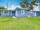 Charming exterior view of a light blue house featuring a well-manicured lawn and bright natural light at 302 E Drury Ave, Kissimmee, FL 34744