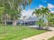 Exterior front view of the home with mature trees and landscaping in yard at 302 E Drury Ave, Kissimmee, FL 34744
