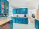 This kitchen features sleek stainless steel appliances and bold blue cabinetry with butcher block countertops at 302 E Drury Ave, Kissimmee, FL 34744