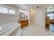 Light-filled bathroom with soaking tub, natural wood vanity, and white tile flooring at 3048 Cherokee Rd, St Cloud, FL 34772