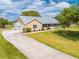 Inviting exterior of a single-story home with a long driveway and a well-maintained lawn and metal roof at 3048 Cherokee Rd, St Cloud, FL 34772