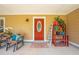 Charming covered front porch with comfortable seating and bright pops of color with plants and decorations at 3048 Cherokee Rd, St Cloud, FL 34772
