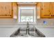 A bright kitchen sink under a window, framed by light wood cabinets and a neutral countertop at 3048 Cherokee Rd, St Cloud, FL 34772