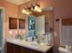 Bathroom featuring dual sinks, neutral countertops, and a large mirror at 3638 Doe Run Dr, St Cloud, FL 34772