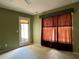 Bright bedroom showcasing a ceiling fan, large window with curtains, and a convenient outdoor access door at 3638 Doe Run Dr, St Cloud, FL 34772
