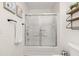 Bright bathroom displays a tub with sliding glass doors, stylish towel rack and shelves on the adjacent wall at 4722 Flagler Beach Way, Kissimmee, FL 34746