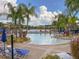 Large community pool surrounded by palm trees, lounge chairs, and umbrellas with lake views at 4722 Flagler Beach Way, Kissimmee, FL 34746