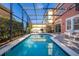 A serene backyard pool and patio area surrounded by a screen enclosure, with lounge chairs, grill, and an umbrella table at 4722 Flagler Beach Way, Kissimmee, FL 34746