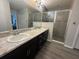 Bathroom with a double sink vanity, granite counters, large mirror and a glass-enclosed shower at 561 Vittorio Dr, Winter Haven, FL 33884