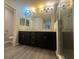 Bathroom featuring a double sink vanity, dark wood cabinets, granite countertops, and a glass-enclosed shower at 561 Vittorio Dr, Winter Haven, FL 33884